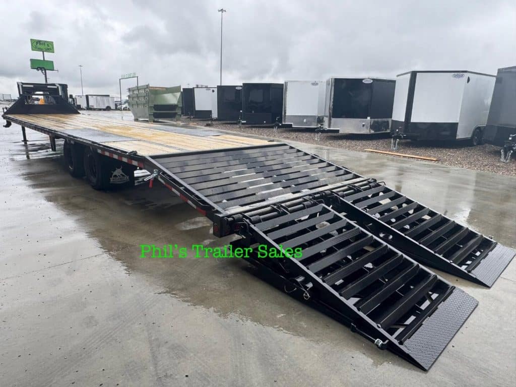 2026 Iron Bull 102 X40 deckover trailer in black, rear view with monster ramps lowered on wet ground.