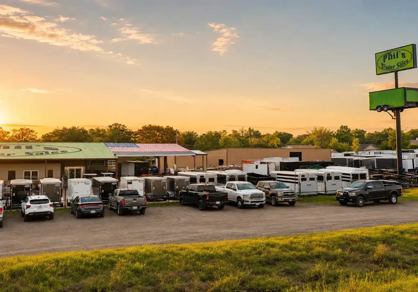3:56 PM Phil's Trailer Sales dealership lot in Waco, Texas at sunset, with a large selection of enclosed, cargo, and livestock trailers on display alongside the storefront building and road sign.